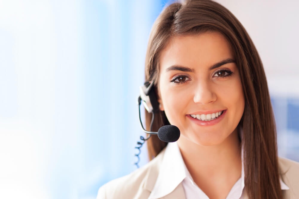 Mulher sorrindo com headset, representando o atendimento ao cliente para o blog Seiva Pura de skincare e ativos cosméticos.