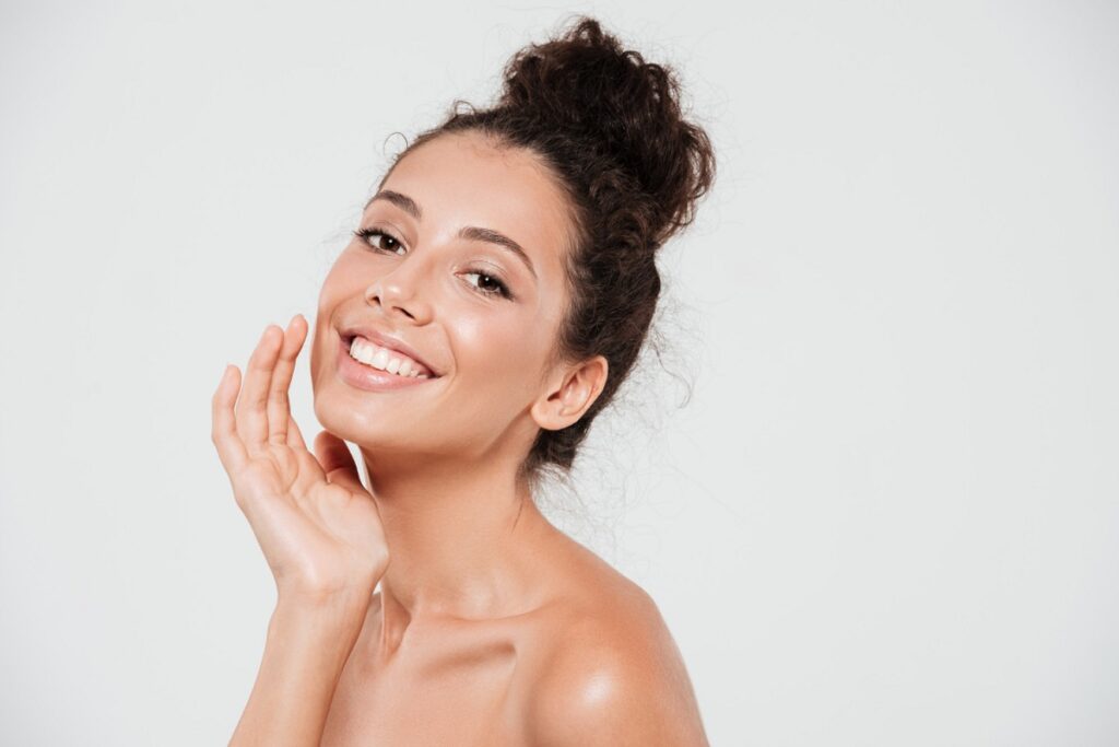 Mulher sorrindo com pele radiante e saudável, representando os benefícios da renovação celular com ativos esfoliantes